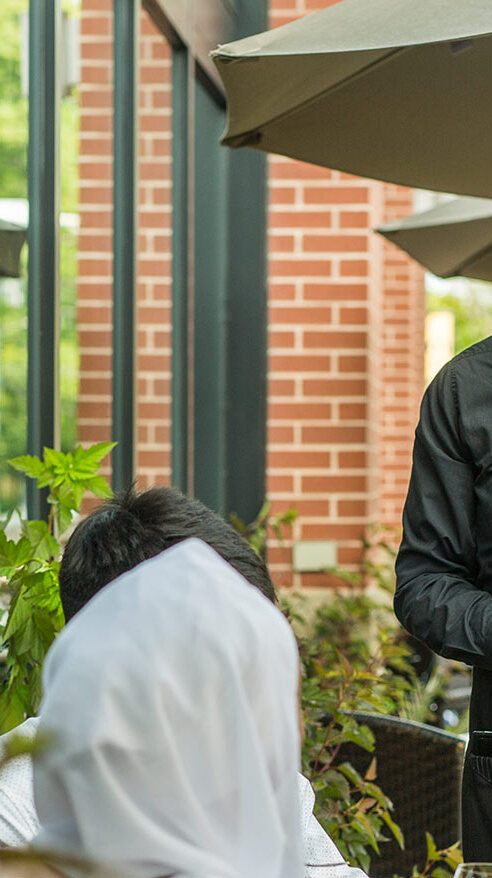 A waiter serving champagne to a group of diners at the Redwater Rustic Grille
