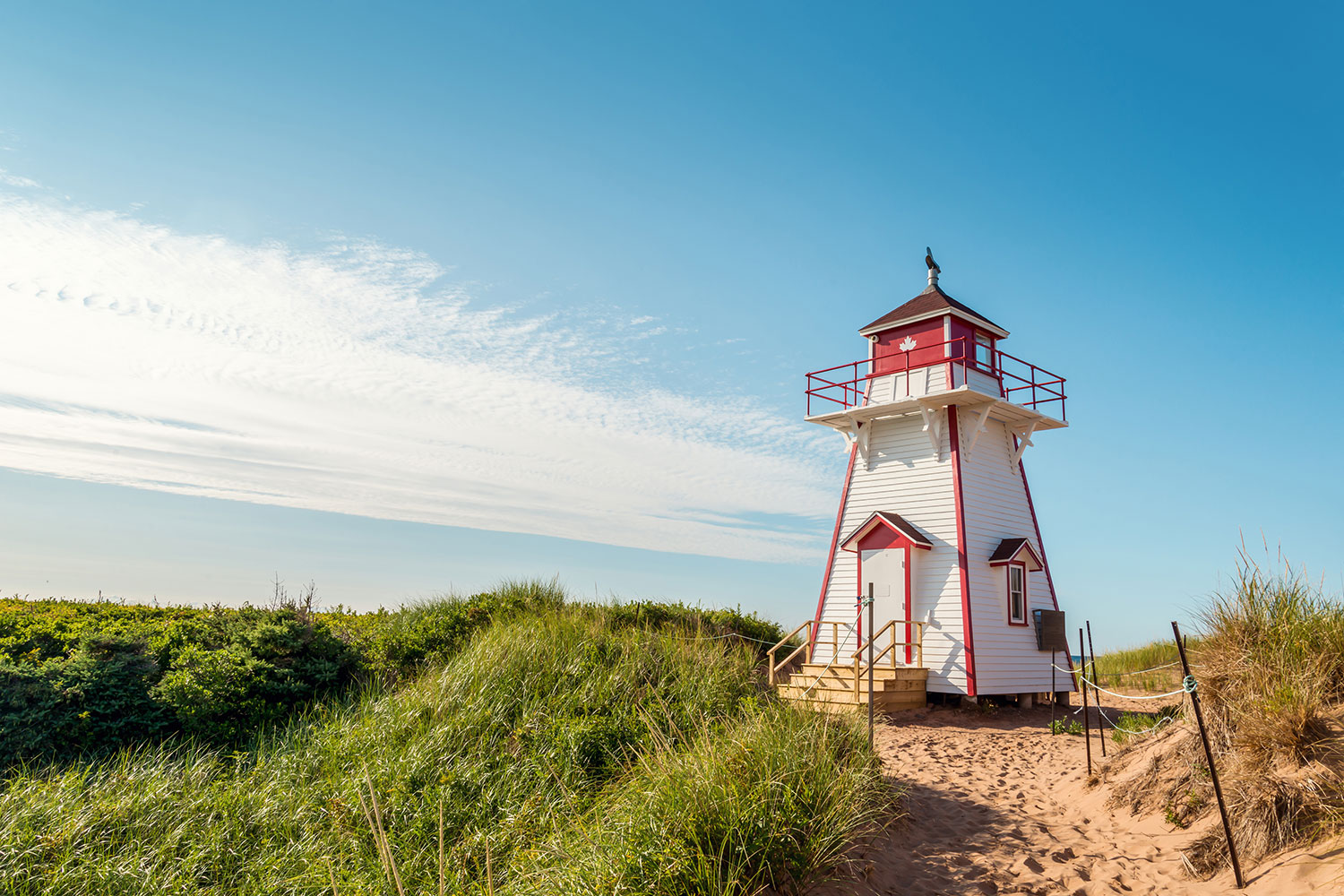 A red and white lighthouse amongst a green landscape